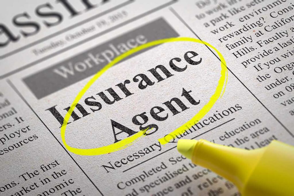 A person reviews auto insurance paperwork with a calculator beside a set of car keys on a kitchen table.